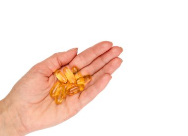 Beyaz arka planda Omega-3 kapsüllerini tutan bir kadının eli. Kalp sağlığı, bağışıklık desteği ve dengeli beslenme için besin takviyesi. Tıbbi konsept, üst görünüm, yakın çekim..