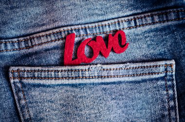 Kırmızı, mavi kot pantolonun cebinde duran kelime sevgisini hissetti. Şefkatli duyguları ve içten aşkı sembolize etti. Yumuşak Sevgililer Günü havası. Üst Manzara. Düz Yatay.