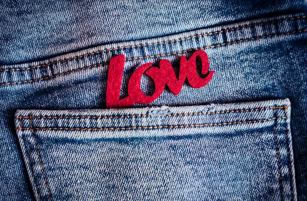 Kırmızı, mavi kot pantolonun cebinde duran kelime sevgisini hissetti. Şefkatli duyguları ve içten aşkı sembolize etti. Yumuşak Sevgililer Günü havası. Üst Manzara. Düz Yatay.
