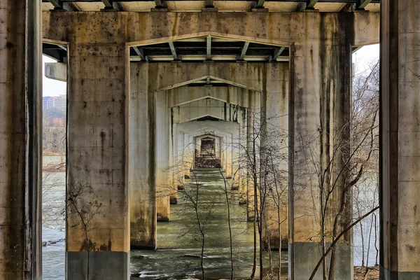 Vista de arcos desde debajo de un viejo puente que cruza un río — Foto de Stock