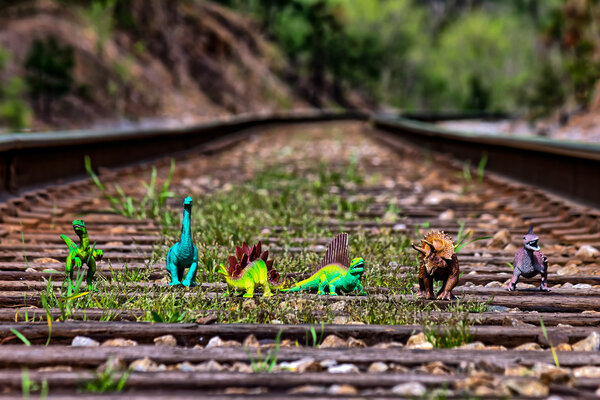 Стая динозавров, идущих по железнодорожным путям
