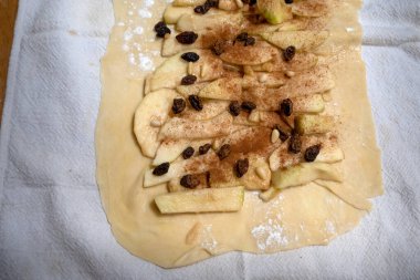 Apfelstrudel assembly rulo hamur üzerine basar: elma dilimleri ve kuru üzümler katman yüzeyine yerleştirilir katman bezi üzerinde dinlenerek, katlanmaya hazır