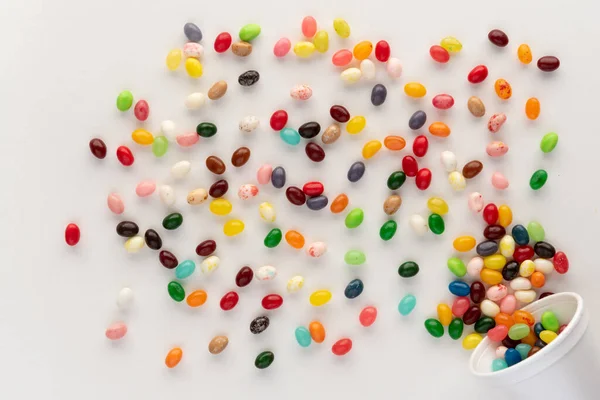 Jelly Bönor Spiller Från Vitt Skum Kopp Mot Vit Bakgrund — Stockfoto