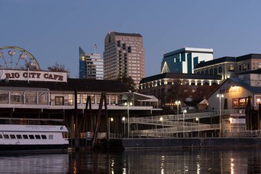 Sacramento, CA, 19 Aralık 2020, Capitol Mall ile Old Sacramento nehrin karşısındaki West Sacramento 'dan izlenen Noel ağacı, Rio City Cafe' nin bir bölümü, Joe yengeçleri ve kamu limanı