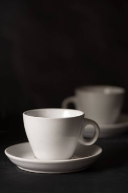 İki boş espresso fincanı siyah arka planda görünüyor. 