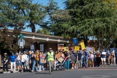 Davis, CA, 18 Ekim 2025. Donald Trump 'a karşı düzenlenen protesto sırasında göstericiler bir Amerikan bayrağı ve Kral Yok ve ICE işareti taşıyorlar