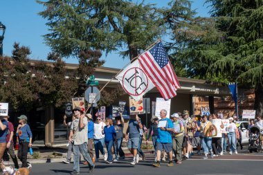 Davis, CA, 18 Ekim 2025. Donald Trump 'a karşı düzenlenen protesto sırasında göstericiler bir Amerikan bayrağı ve Kral Yok ve ICE işareti taşıyorlar