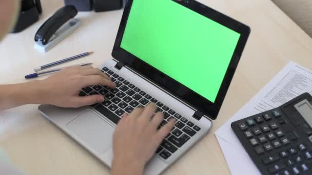 Sulla spalla di una donna che digita su un computer portatile con uno schermo verde-chiave . — Video Stock