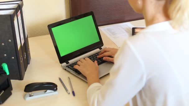 Over het schot van de schouder van een vrouw te typen op een laptop met een sleutel-groen scherm. — Stockvideo