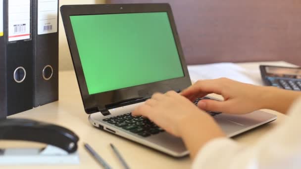 Über der Schulter einer Frau, die auf einem Laptop mit einem schlüssel-grünen Bildschirm tippt. — Stockvideo