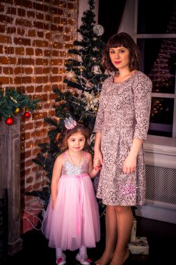Mutlu anne kızıyla Noel ağacı yakınındaki şömine tarafından birlikte