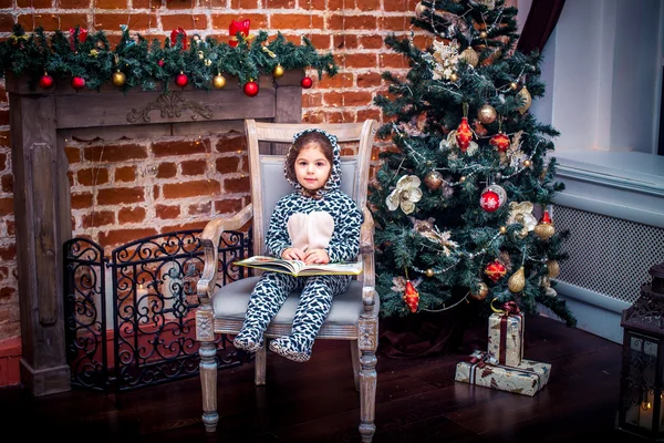 Szép kislány, mosolygós, mackó közelében a karácsonyfa, vintage széken ül. Boldog Új Évet. — Stock Fotó