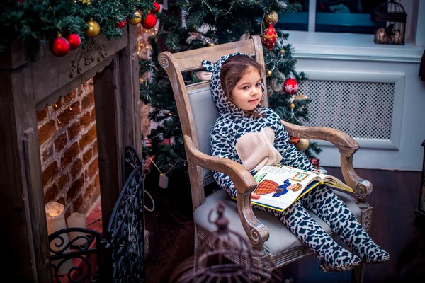 Jolie petite fille souriante avec un ours en peluche près du sapin de Noël assis sur une chaise vintage. Bonne année . — Photo