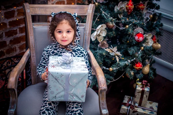 Jolie petite fille souriante avec un ours en peluche près du sapin de Noël assis sur une chaise vintage. Bonne année . — Photo