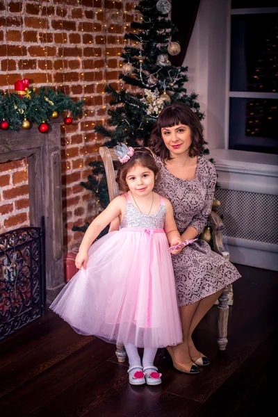 Mãe feliz com sua filha junto à lareira perto da árvore de Natal — Fotografia de Stock