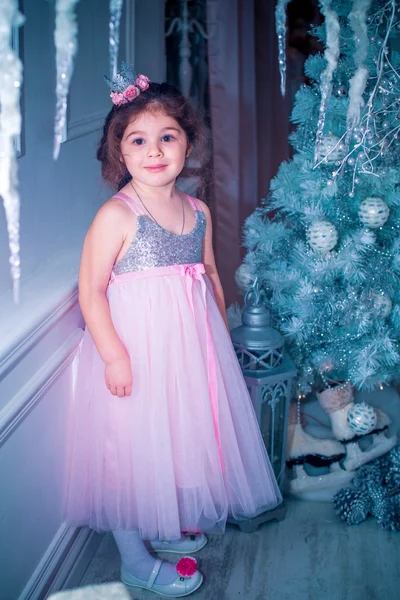 Menina vestida de forma bonita vestido de flor branca posando perto da árvore de Natal — Fotografia de Stock