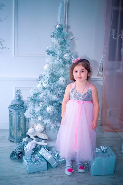 Menina vestida de forma bonita vestido de flor branca posando perto da árvore de Natal — Fotografia de Stock