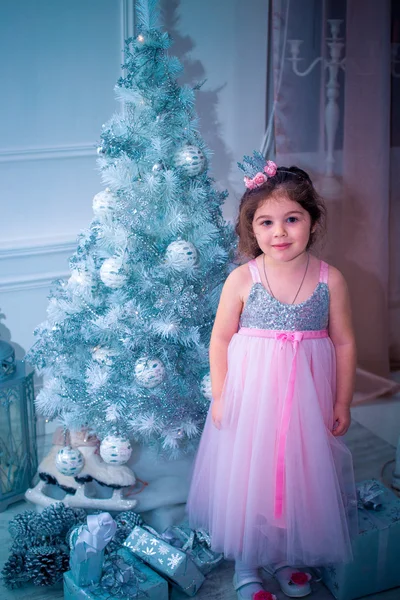 Menina vestida de forma bonita vestido de flor branca posando perto da árvore de Natal — Fotografia de Stock