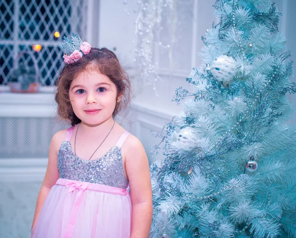 Menina vestida de forma bonita vestido de flor branca posando perto da árvore de Natal — Fotografia de Stock