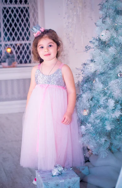 Menina vestida de forma bonita vestido de flor branca posando perto da árvore de Natal — Fotografia de Stock