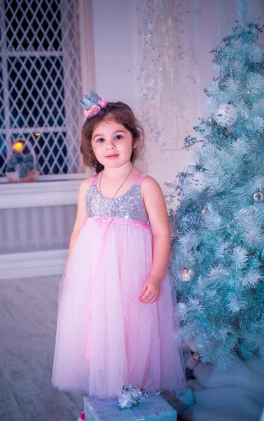 Menina vestida de forma bonita vestido de flor branca posando perto da árvore de Natal — Fotografia de Stock