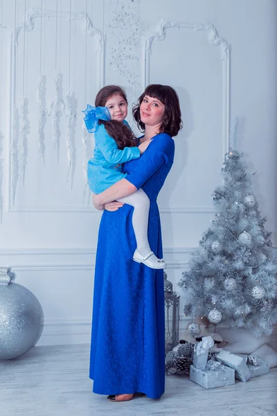 Mãe feliz com sua filha em vestidos azuis longos ficar perto da árvore de Natal — Fotografia de Stock