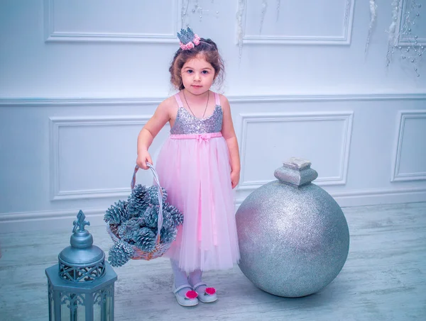 Маленька дівчинка в красивій моді біла квіткова сукня позує біля ялинки Ліцензійні Стокові Фото