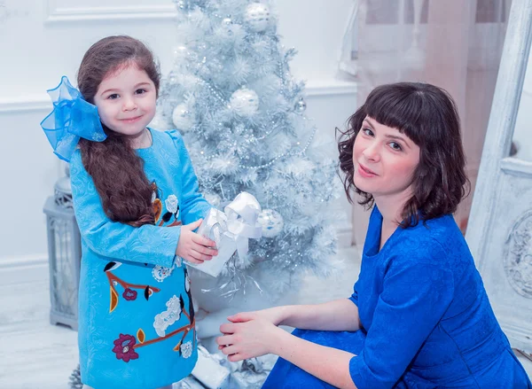 Mère heureuse avec sa fille dans de longues robes bleues debout près du sapin de Noël — Photo