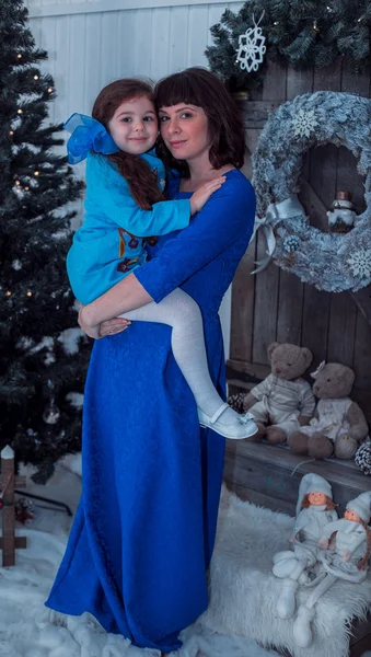 Mãe feliz com sua filha em vestidos azuis longos ficar perto da árvore de Natal — Fotografia de Stock