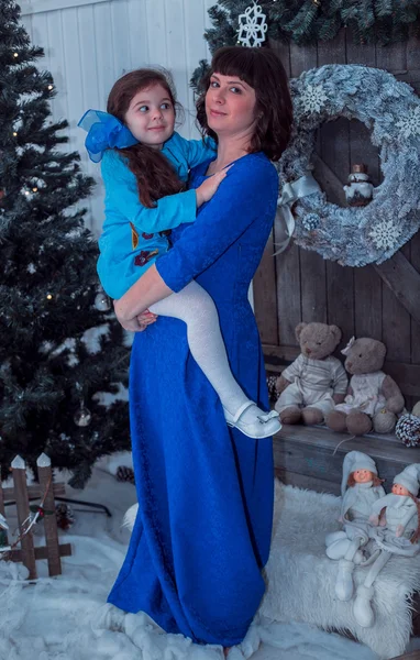 Mère heureuse avec sa fille dans de longues robes bleues debout près du sapin de Noël — Photo