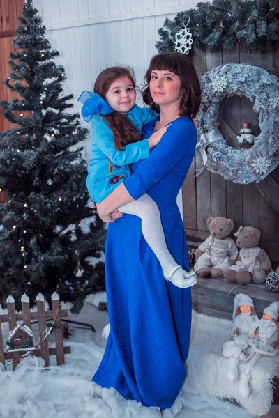 Mãe feliz com sua filha em vestidos azuis longos ficar perto da árvore de Natal — Fotografia de Stock