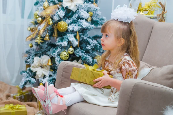 Kislány megnyitása egy ajándék otthon a nappaliban — Stock Fotó