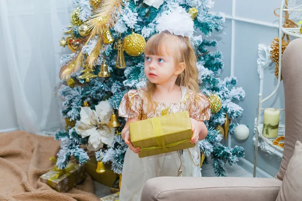 Menina abrindo um presente em casa na sala de estar — Fotografia de Stock