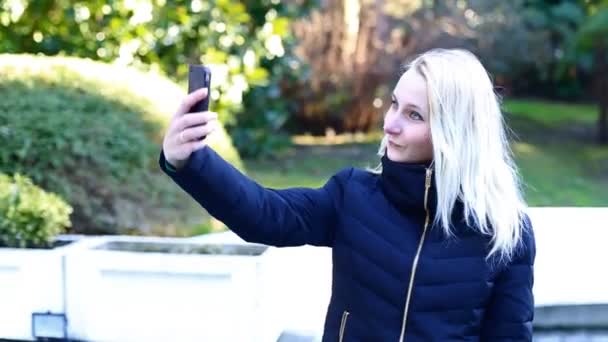 Junge attraktive glückliche Frau erschießt sich im Park - Selfie — Stockvideo