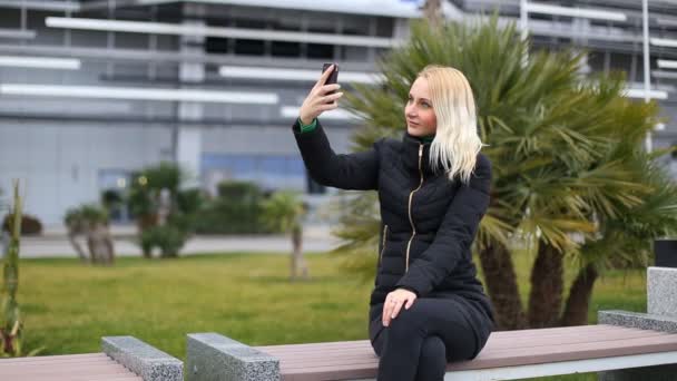 Unga attraktiva glad kvinna skjuter sig själv i park - selfie — Stockvideo