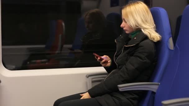 Тексты смс на телефон, молодая женщина в поезде — стоковое видео