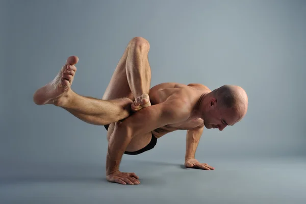 Hombre de yoga posando sobre un fondo gris — Foto de Stock
