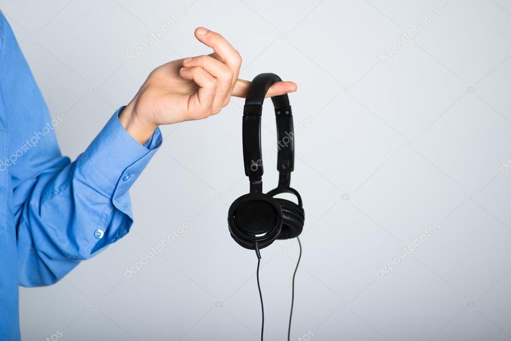 man's hand holding stylish headphones. advertising concept, isolated on a gray background.