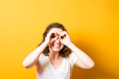 Kız ellerini dürbünle gösteriyor.