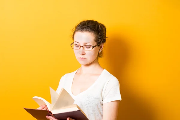 Ein helles brünettes Mädchen mit Brille liest ein Buch — Stockfoto