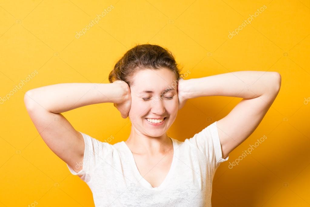 a bright girl covers ears with  hands