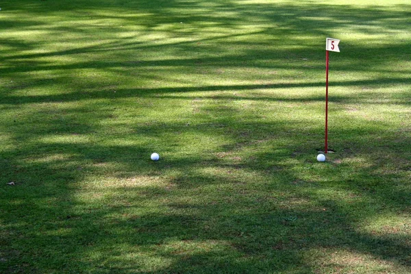 Par de pelotas de golf cerca de bandera agujero 5 — Foto de Stock