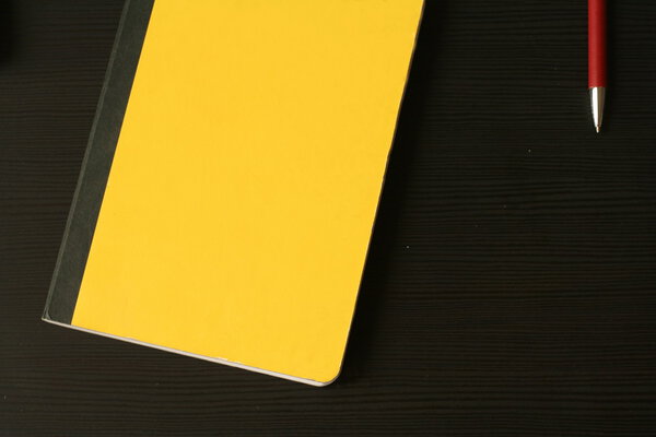 Top view on the yellow scratchpad (notebook) with red pencil