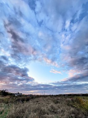 Kuru kırsal alan engin bir gökyüzü altında alacakaranlıkta dinamik bulutlarla kaplanıyor.