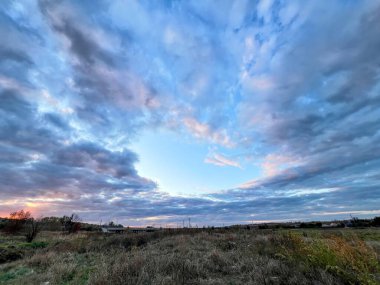 Akşam günbatımında kırsal alanda dramatik bulutlar dairesel şekil alıyor.