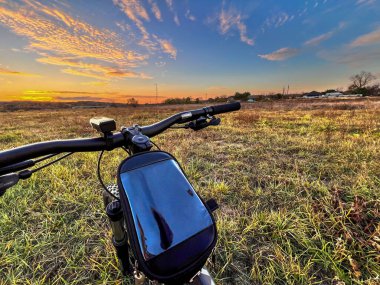 Bisiklet gidonu perspektifi gün batımında altın bir arazide gezintiye çıkıyor.