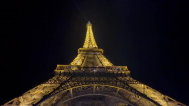 Ünlü Eyfel kulesi, Paris 'teki karanlık gökyüzüne karşı altın ışıklarla aydınlatılmış.