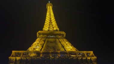 Fransa 'nın başkenti Paris' te gece karanlığında altın ışıklarla parıldayan ünlü Eyfel kulesi.