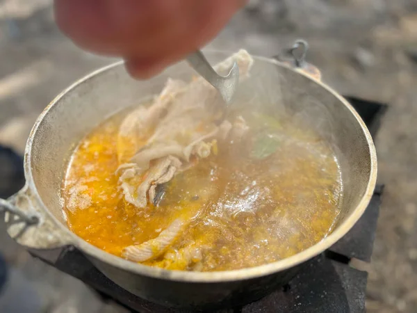 Dışarıdaki ateşin üzerine metal tencerede kaynamış çorbaya balık parçaları ekliyorum.