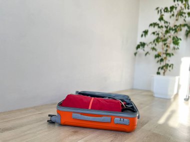 Kırmızı elbiseli turuncu bavul, yolculuğa hazır.